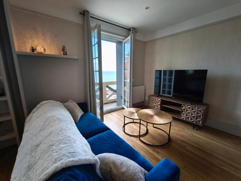 a living room with a blue couch and a television at L'Harmonie des Vagues in Granville