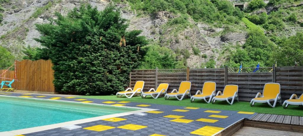 un groupe de chaises assises à côté d'une piscine dans l'établissement Camping New Rabioux, à Châteauroux-les-Alpes