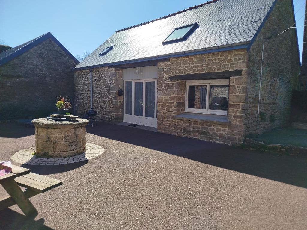 une maison en pierre avec un banc devant elle dans l'établissement Gîte au charme champêtre, à Guern