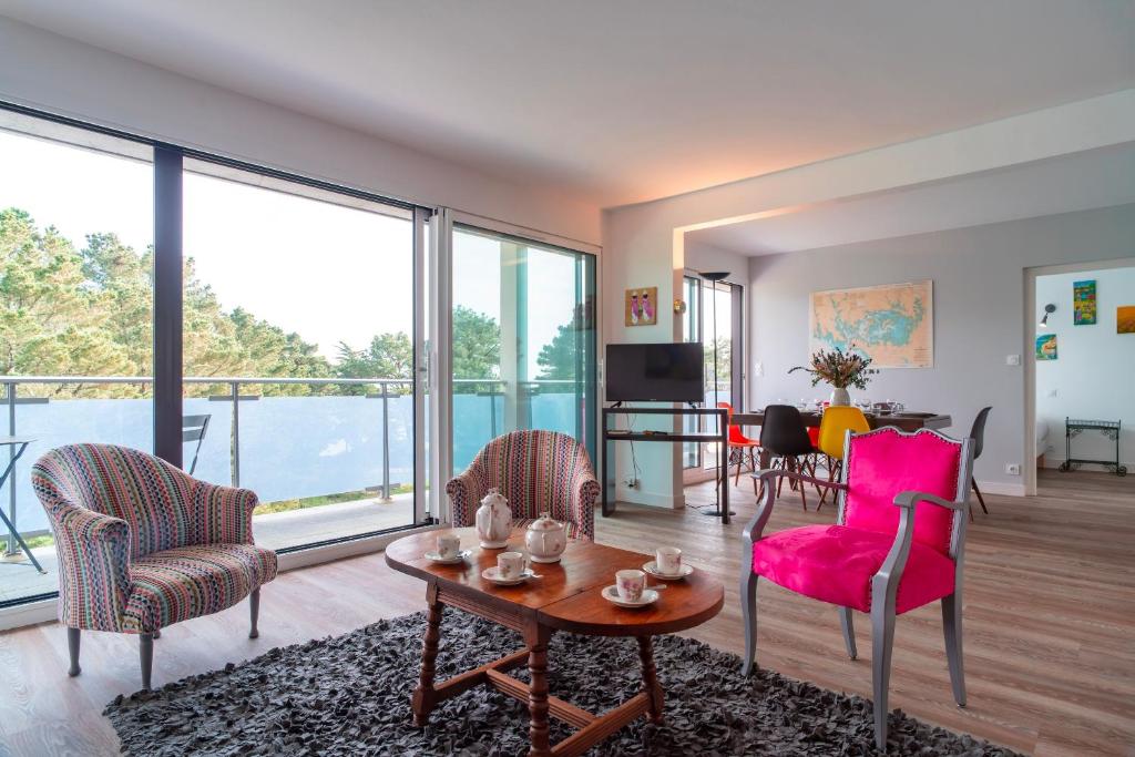 - un salon avec des chaises roses et une table dans l'établissement La perle de Men Er Beleg - Appt vue mer de 167m², à Saint-Philibert