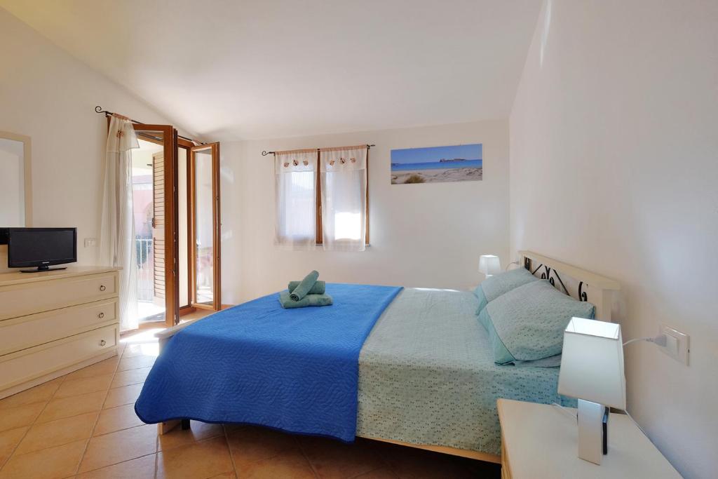 um quarto branco com uma cama e uma televisão em Il giardino di Marina em Teulada