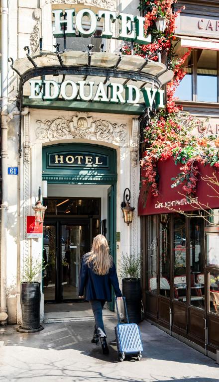 a woman pulling a suitcase in front of a hotel at Hôtel Edouard 6 by Malone in Paris