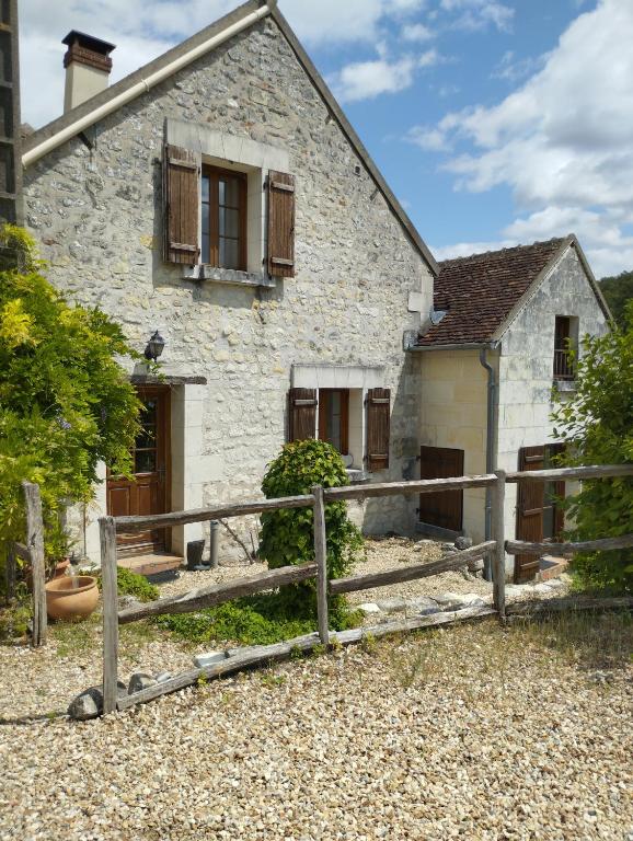 une maison en pierre avec une clôture en bois devant elle dans l'établissement Jolie maison au calme, à Châteauvieux