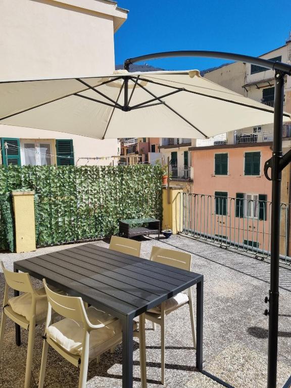 a black table with chairs and an umbrella on a balcony at Vibes 5terre in Riomaggiore