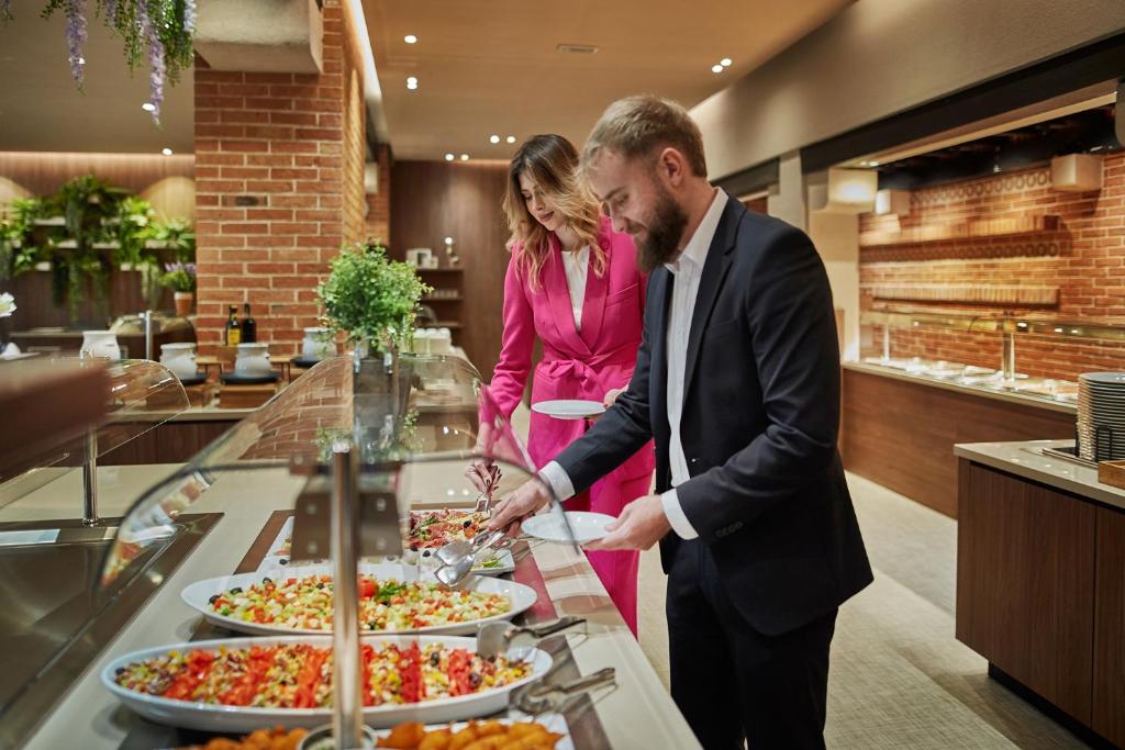 a man and woman preparing food at a buffet at Villas - Hotel & Resort Adria Ankaran in Ankaran
