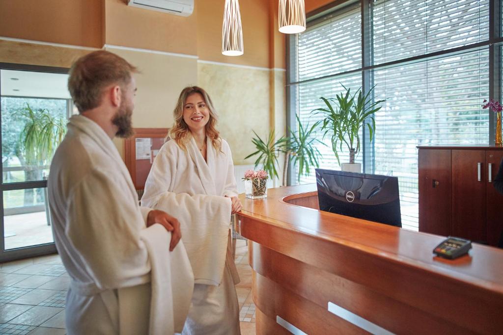 a man and a woman standing in a barber shop at Villas - Hotel & Resort Adria Ankaran in Ankaran