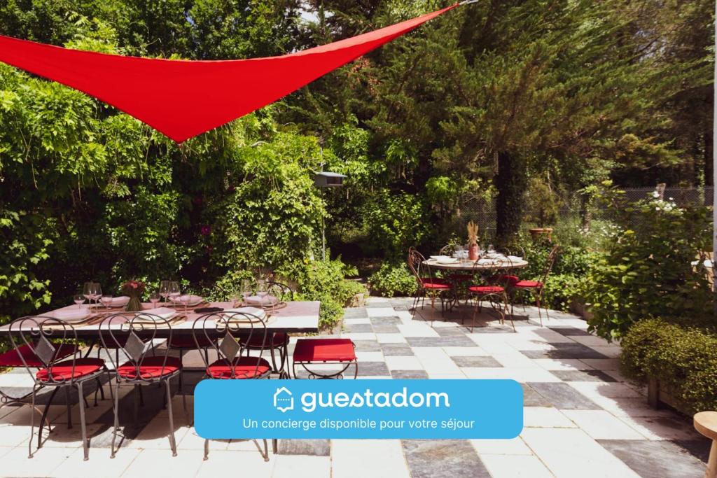 a patio with a table and chairs and a red sheet at Nature et partage - Jacuzzi - Wifi in Grand-Landes