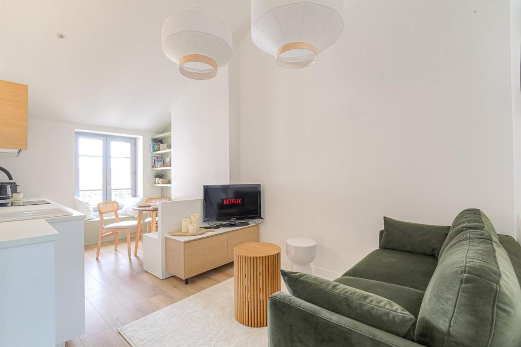 un salon avec un canapé vert et une cuisine dans l'établissement Cocon chaleureux, 4 pers, Lyon 6ème, à Lyon