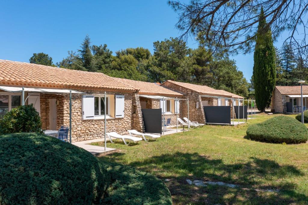 une rangée de cottages avec des chaises et des arbres dans l'établissement Provençal stone T2 Mazet in a tourist residence, à La Roque-sur-Pernes