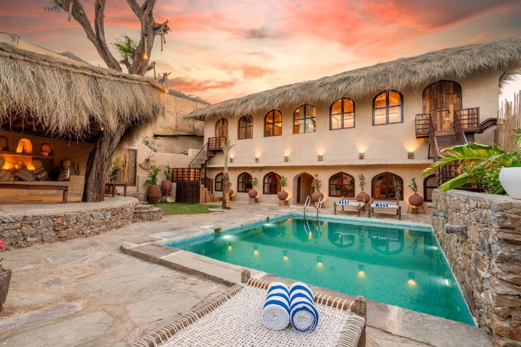 Sunanda by 1810AD - A Boutique Organic Retreat في بوشكار: منزل به مسبح ومنتجع