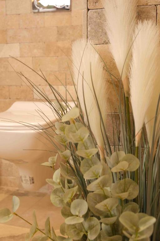 a vase filled with plants next to a toilet at Phellos Suites Boutique Hotel in Şile
