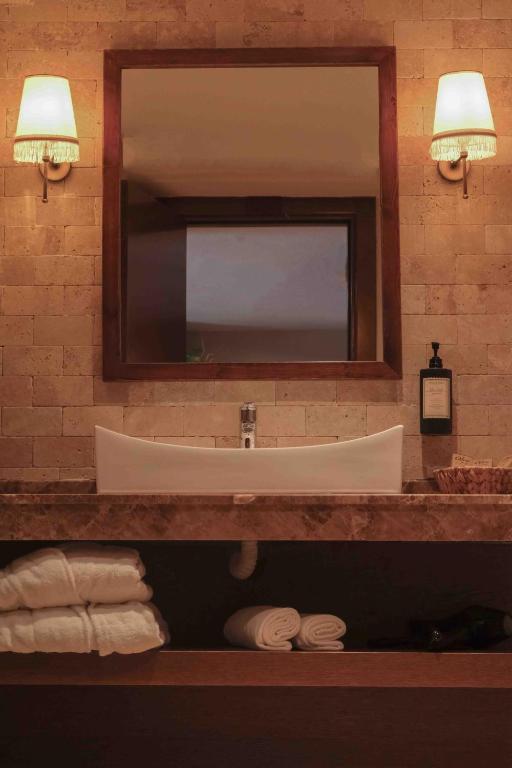 a bathroom with a sink and a mirror and towels at Phellos Suites Boutique Hotel in Şile