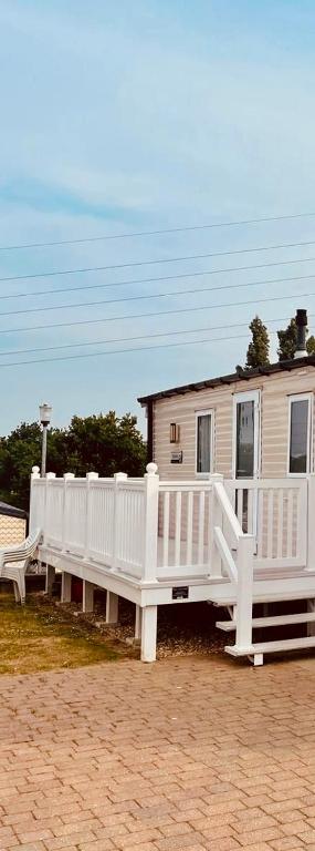 a house with a white porch and a white fence at Caravan in Rockley Park 3 Bedrooms in Poole