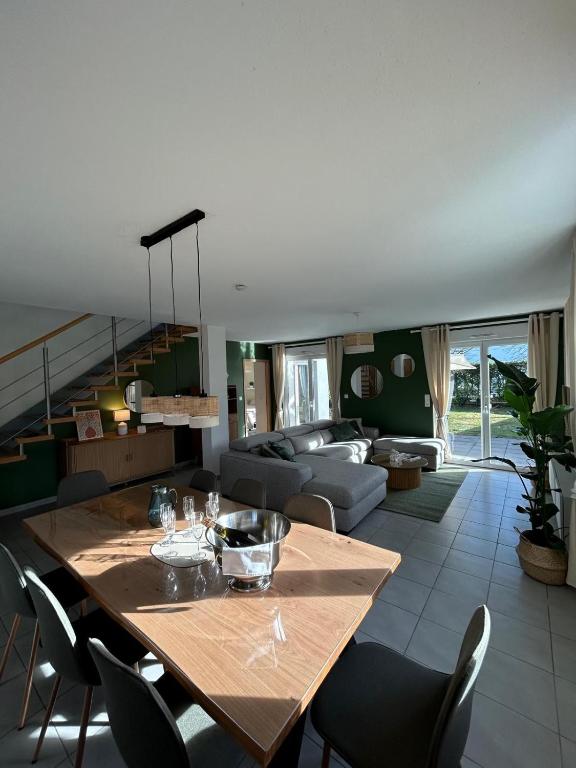 une salle à manger et un salon avec une grande table en bois dans l'établissement Au Coin du Verger, à Colmar
