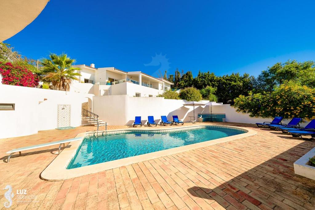 a swimming pool with blue chairs and a house at 180 degree Ocean Views, Pure Paradise in Luz