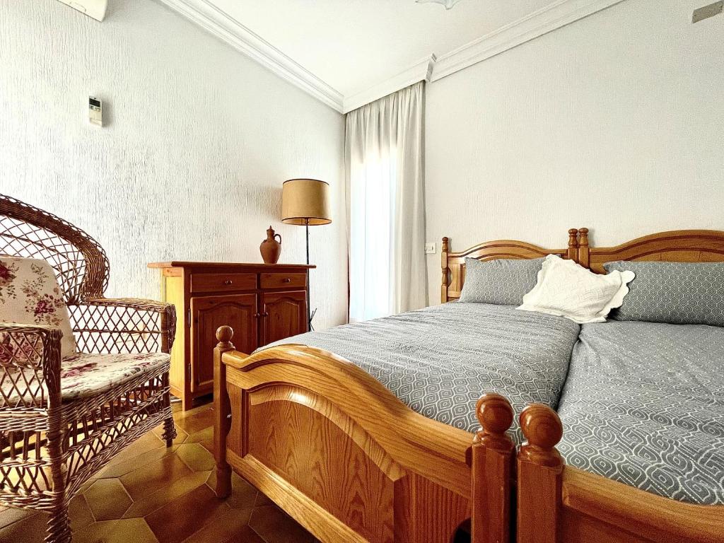 a bedroom with a wooden bed and a chair at Home Campoamor in Orihuela Costa
