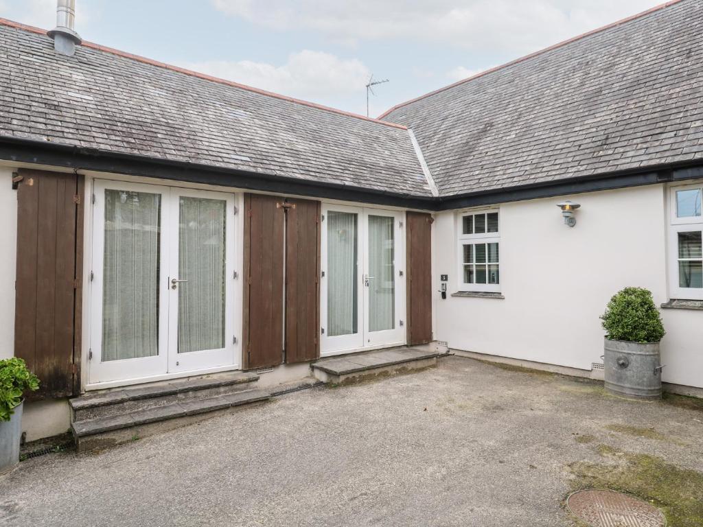 a house with white walls and wooden doors at No 3 The Hinges in Newquay