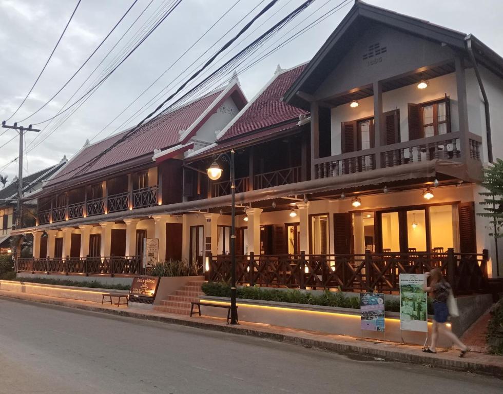 a woman walking down the street in front of a building at Villa Deux Rivières Hotel in Luang Prabang