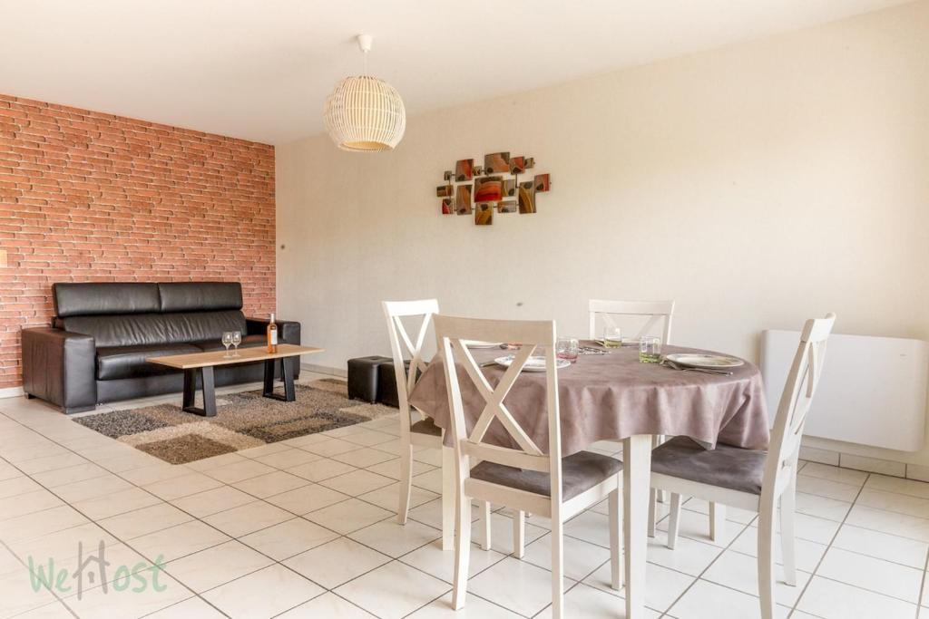 une salle à manger avec une table et un canapé dans l'établissement FRANCIS LE CARVAL - REZE - balcon - parking, à Rezé