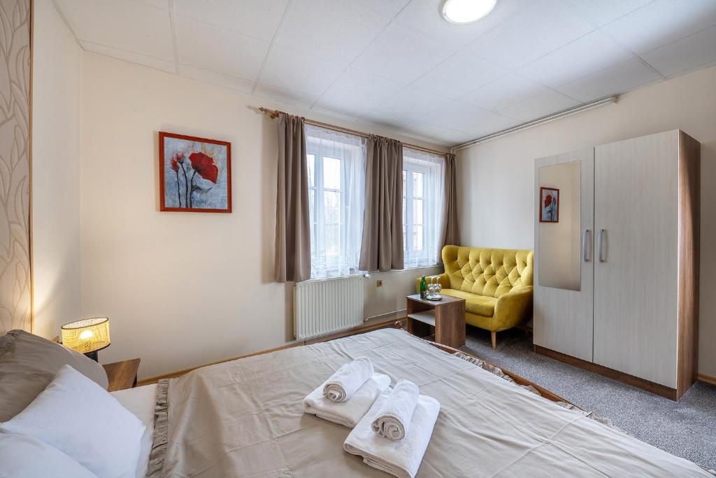 a bedroom with a bed and a yellow chair at Rodinný hotel Myslivna in Třeboň