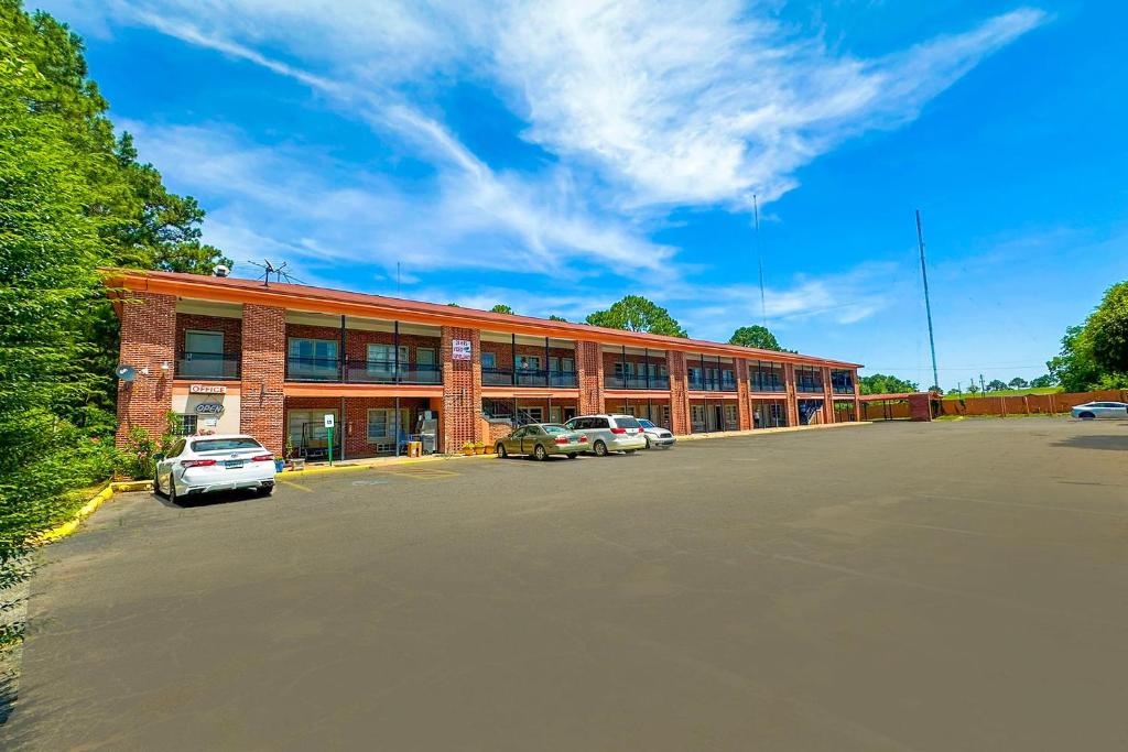 Un gran edificio de ladrillos con coches aparcados en un estacionamiento. en Sunrise Inn By OYO Albany, en Albany