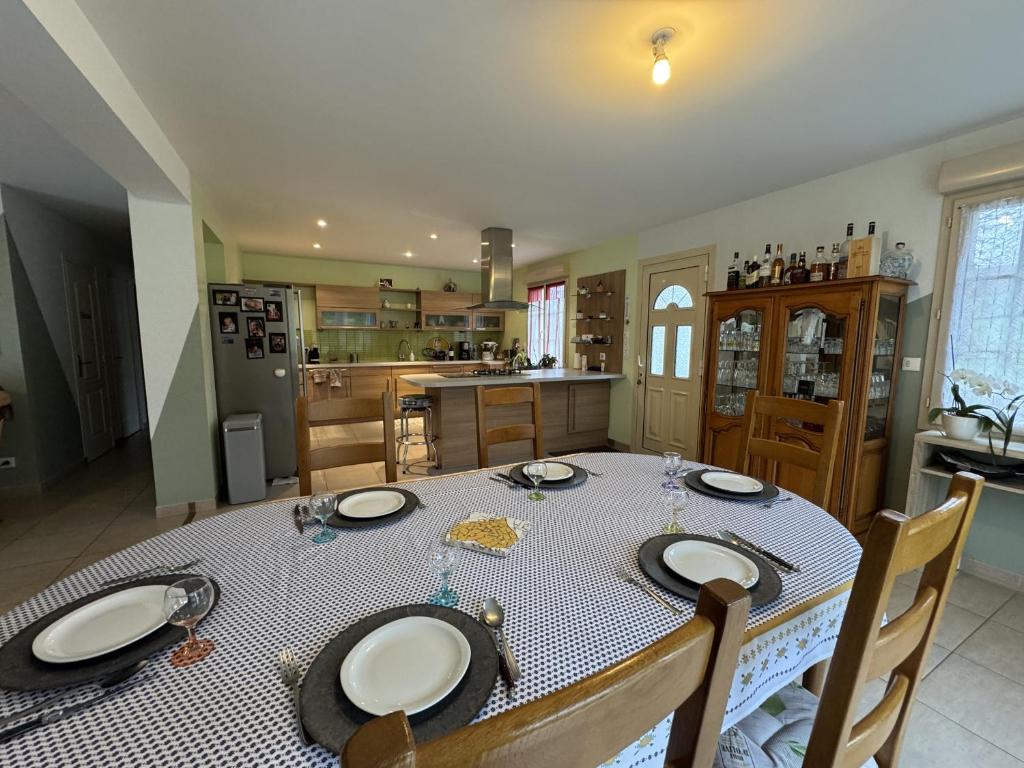 a dining room table with chairs and a kitchen at La Maison de la Tuffiere - 14pers - Circuit Bugatti in Le Grand-Lucé