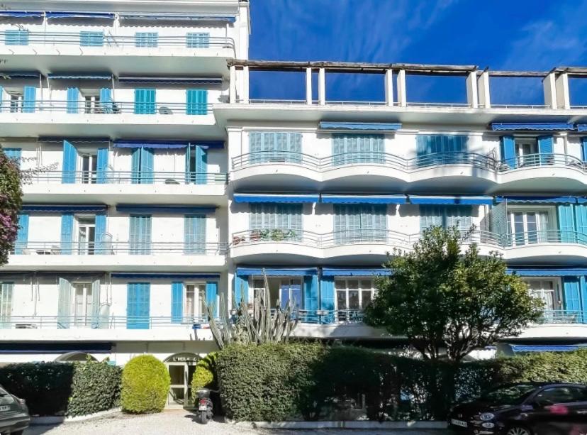 - un immeuble d'appartements blanc avec des buissons en face dans l'établissement Charmant appartement 3p en bord de mer terrasse parking, à Beaulieu-sur-Mer