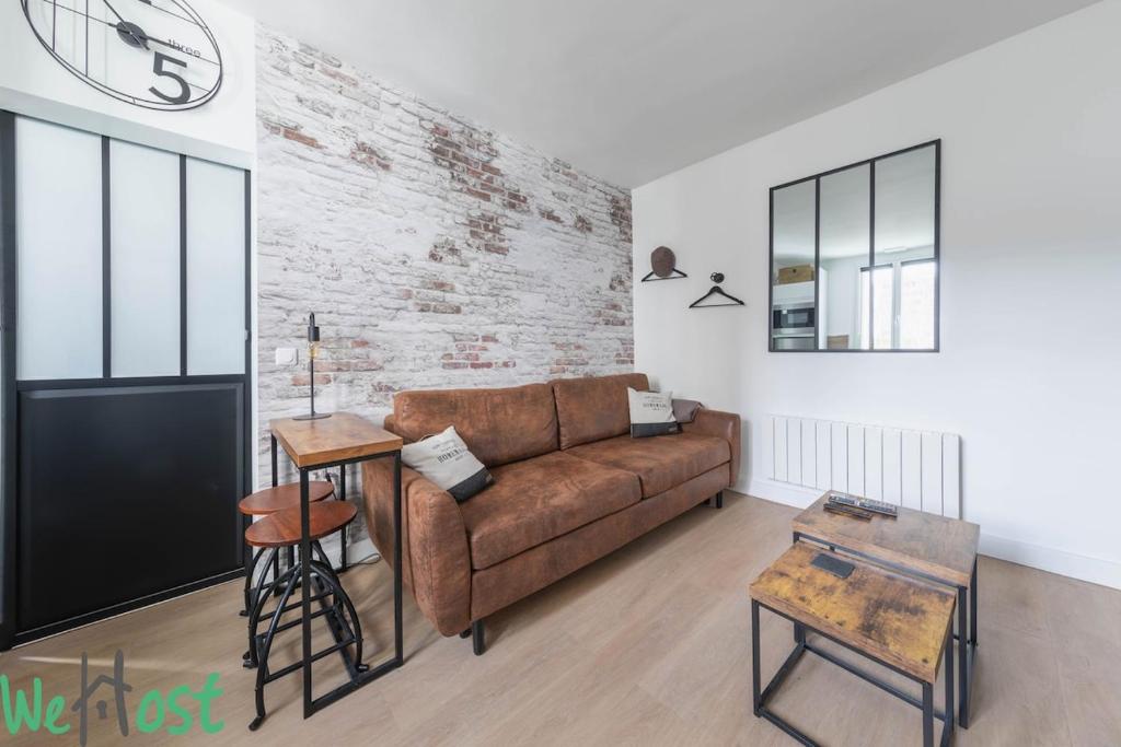 - un salon avec un canapé brun et un mur en briques dans l'établissement Charenton 2 - CI - Paris apt, 2 ppl - Bercy - Gare de Lyon, à Paris