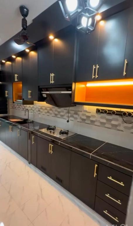 a large kitchen with black and orange cabinets at AZ Homestay Meranti in Pasir Mas