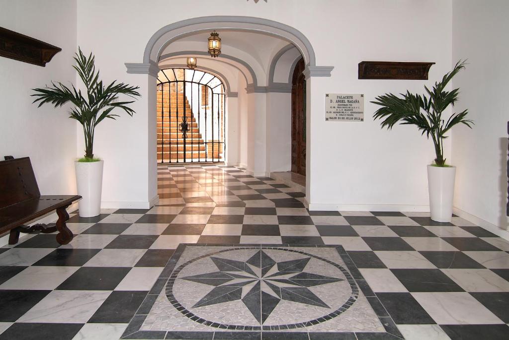 a hallway with a checkered floor and two potted plants at Casa Rural Palacete Magaña in Malón