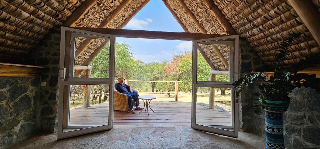 a woman sitting at a table in a room with an open door at Shamba Pori Lodge in Idulo