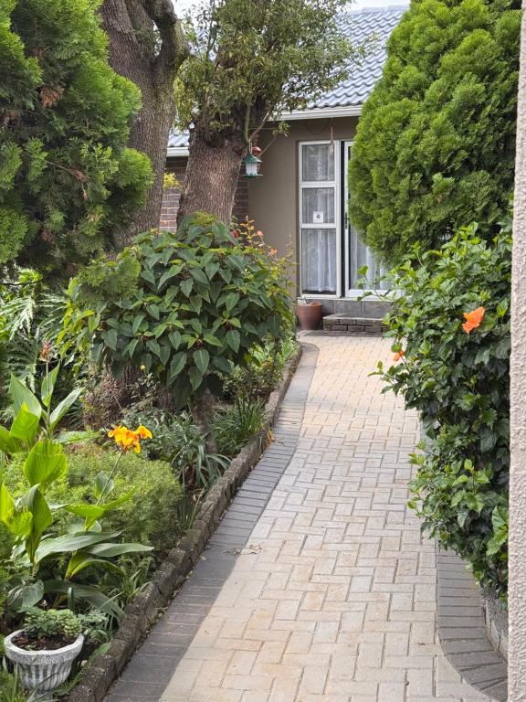 a garden with a brick walkway in front of a house at 15 On Palm East in Edenvale