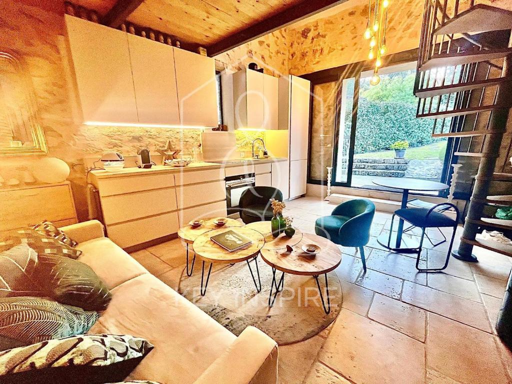 a living room with a couch and tables and a kitchen at La Petite Maison d'Emmanuelle in Le Tignet