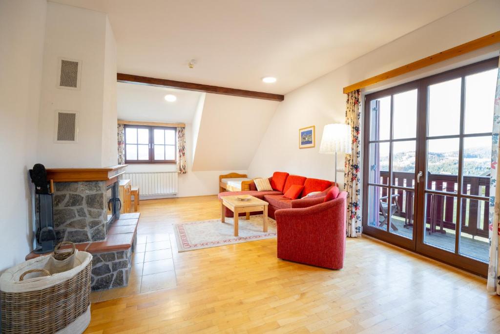 a living room with a fireplace and a red couch at Apartmaji Bar Smučar in Ribnica na Pohorju