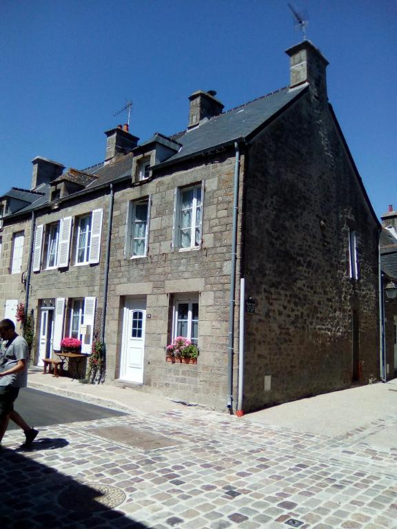 un homme qui passe devant un grand bâtiment en briques dans l'établissement La MAISON DU PECHEUR, à Barfleur