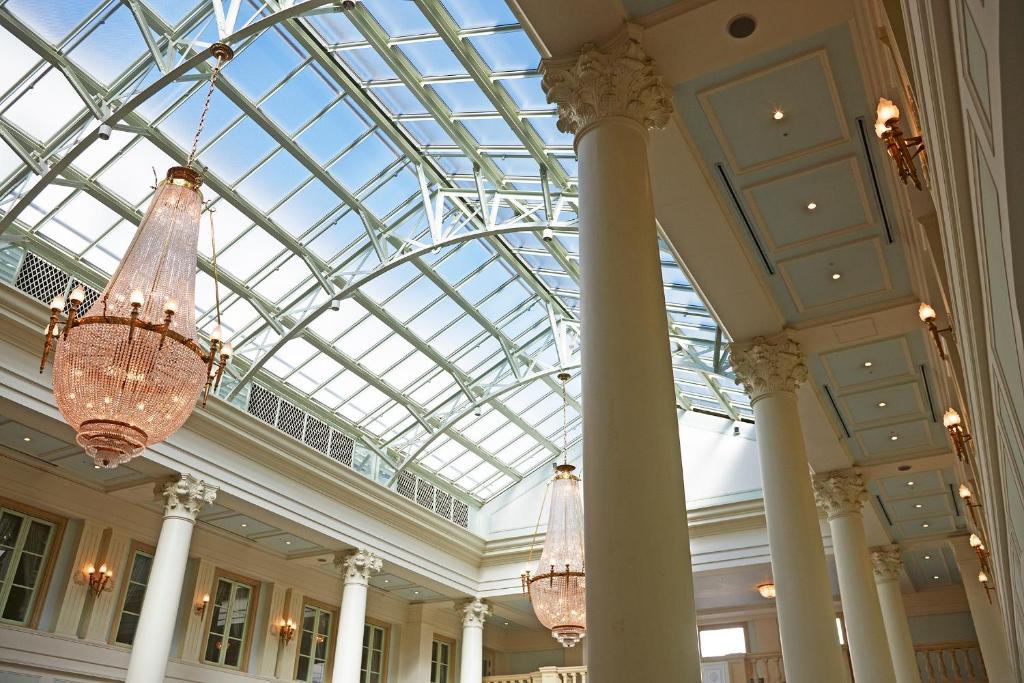 a lobby with chandeliers and a glass ceiling at Hotel Amsterdam Huis Ten Bosch in Sasebo
