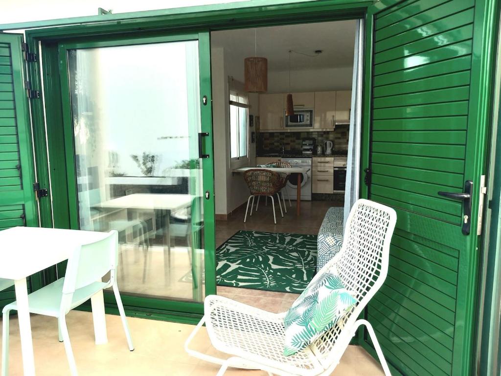 a green house with chairs and a table and a kitchen at Beach house near the sea with pool in Puerto del Carmen