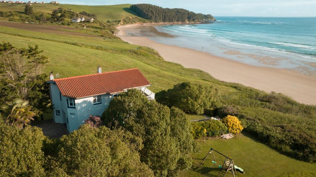 a blue house on a hill next to a beach at Wishome-La casa más especial de Oyambre, Comillas in San Vicente de la Barquera