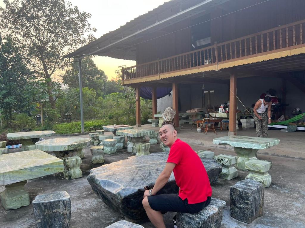 a man sitting on a rock in front of picnic tables at Fish Farm Homestay 1 in Xóm Soi (1)