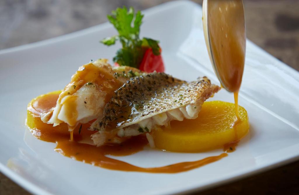 a plate of food with a piece of fish and a lemon at Hotel Amsterdam Huis Ten Bosch in Sasebo