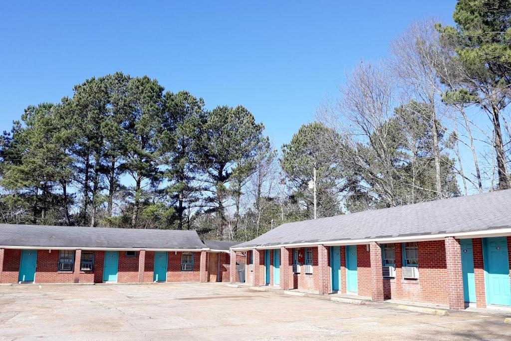 a row of red brick buildings with blue doors at OYO Hotel Durant MS Bowling Green Rd in Durant