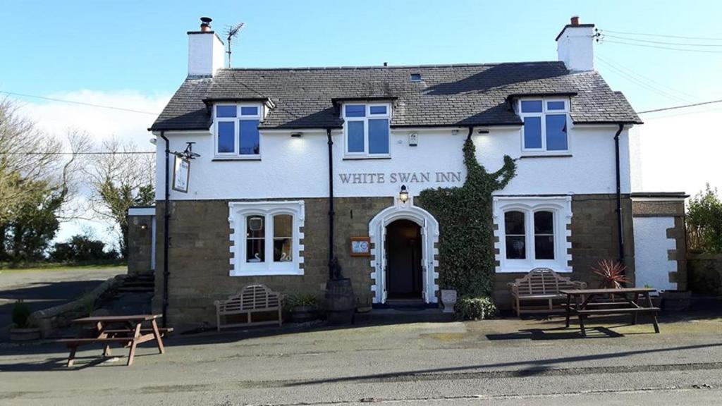 uma estalagem de estrelas brancas com dois bancos à frente em White Swan Inn em Belford