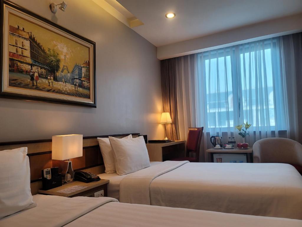 a hotel room with two beds and a window at Luxeden Hotel Hanoi in Hanoi