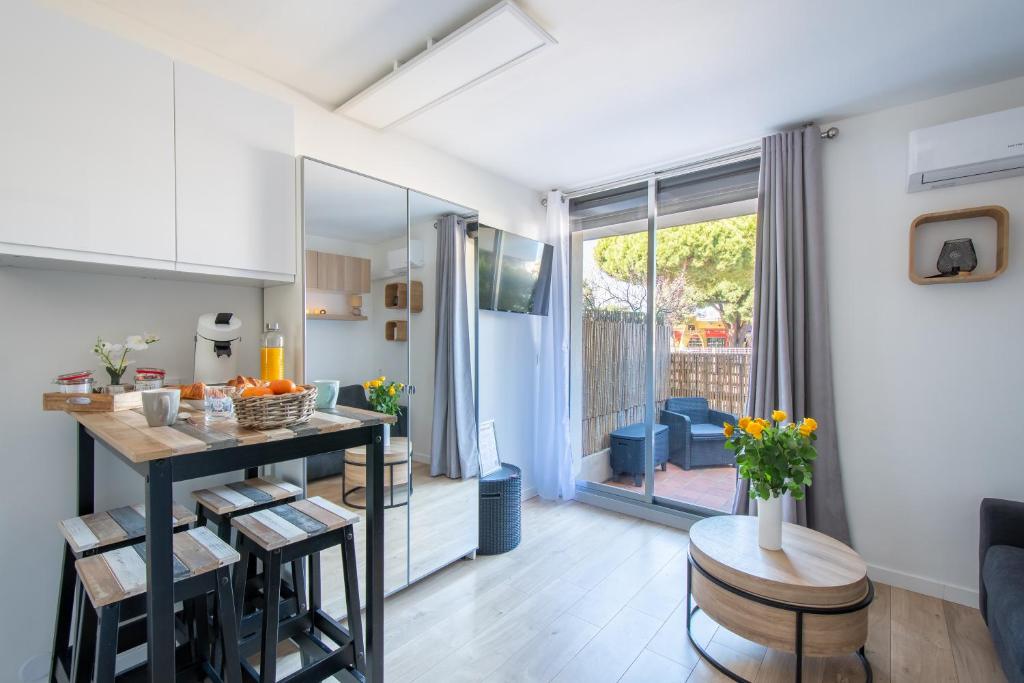 une cuisine et un salon avec une table et des chaises dans l'établissement Le Cabestan Studio Terrasse Parking Proche de la plage et de la Marina de Port Camargue, au Grau-du-Roi