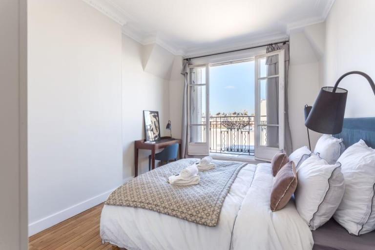 a bedroom with a large bed with a large window at GuestReady - Designer Apartment - Eiffel Tower View! in Paris