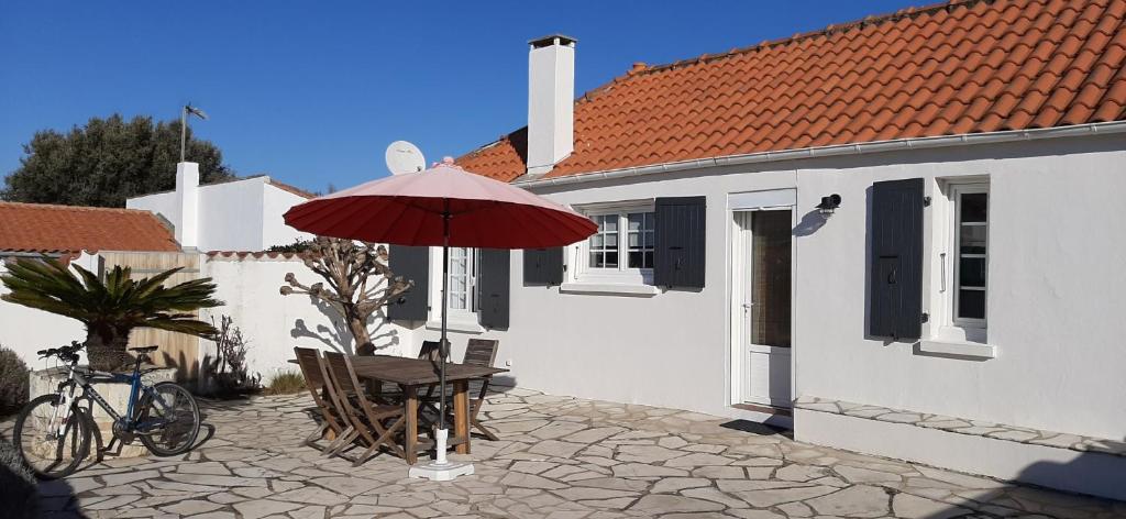 une table avec un parasol devant un bâtiment dans l'établissement La Tidette, à Sainte-Marie de Ré