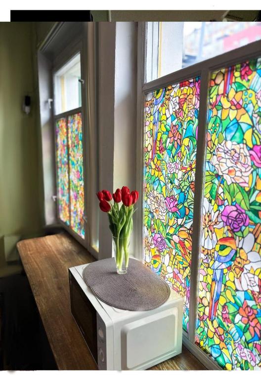 a vase of red tulips on a microwave with a stained glass window at Chisinau Hostel in Chişinău
