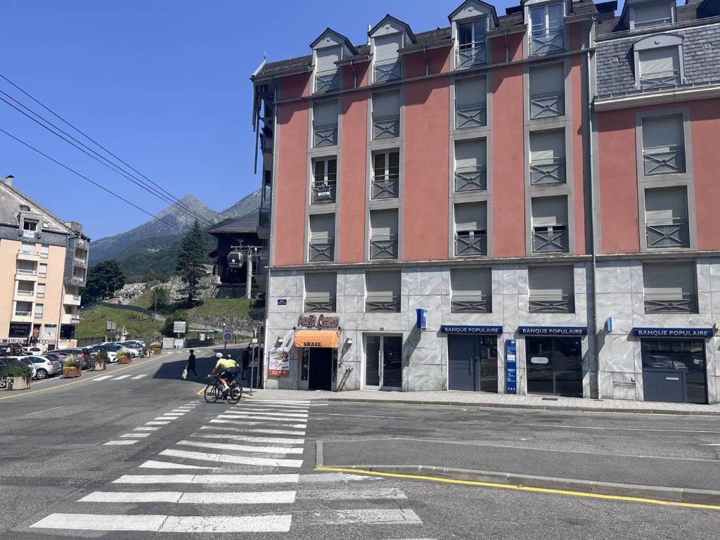 une personne à vélo dans une rue à côté d'un bâtiment dans l'établissement T2 à Cauterets avec alcôve, proche parking - FR-1-812-119, à Cauterets