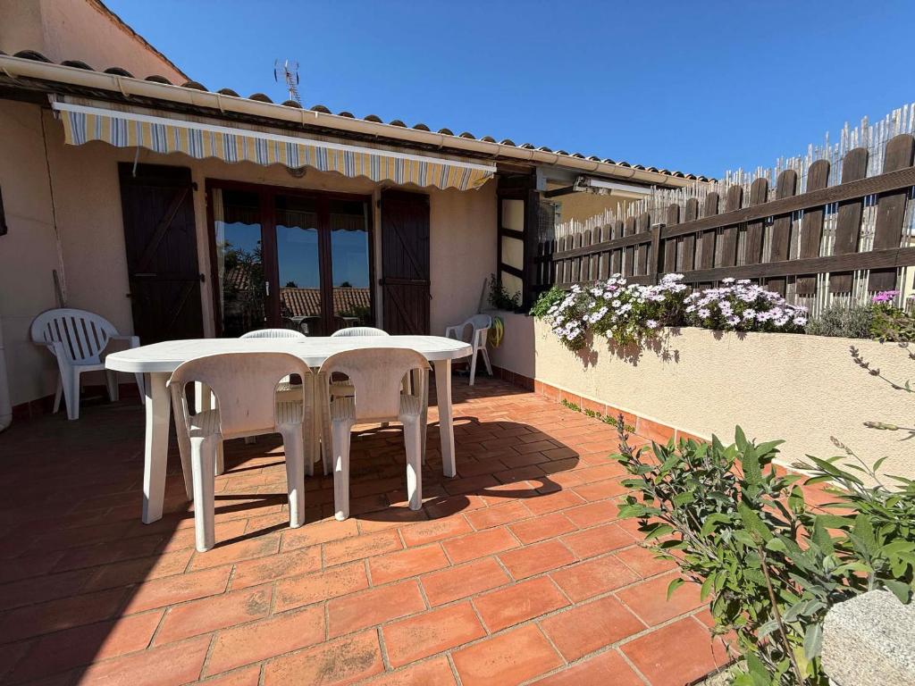 d'une terrasse en briques avec une table et des chaises blanches. dans l'établissement Villa 4/6 pers. au calme, proche port, parking privé - FR-1-784-39, à Gruissan