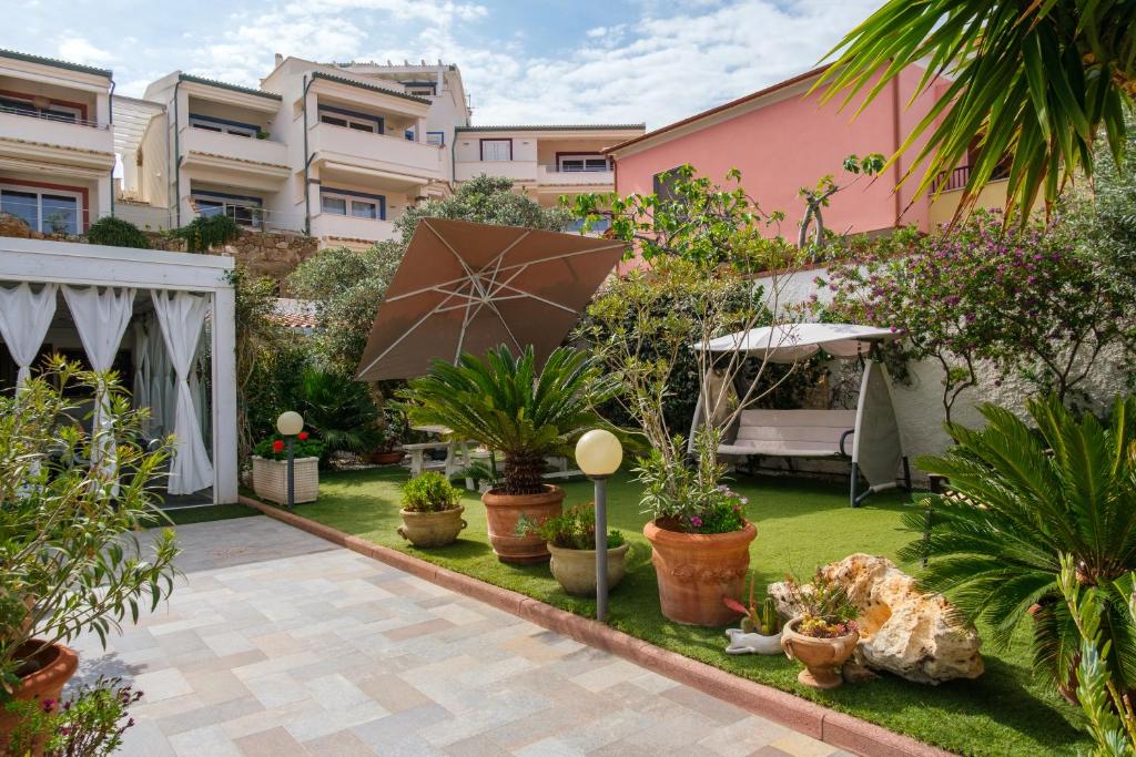 ogród z doniczkami i parasolem w obiekcie Villa Piana w mieście Castelsardo